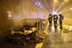 Ein ausgebrannter Pkw am Rand eines Tunnels.