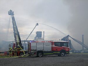 Mit Drehleitern bauten die Einsatzkräfte eine Riegelstellung auf, um weitere Gebäude vor dem Großbrand zu schützen.