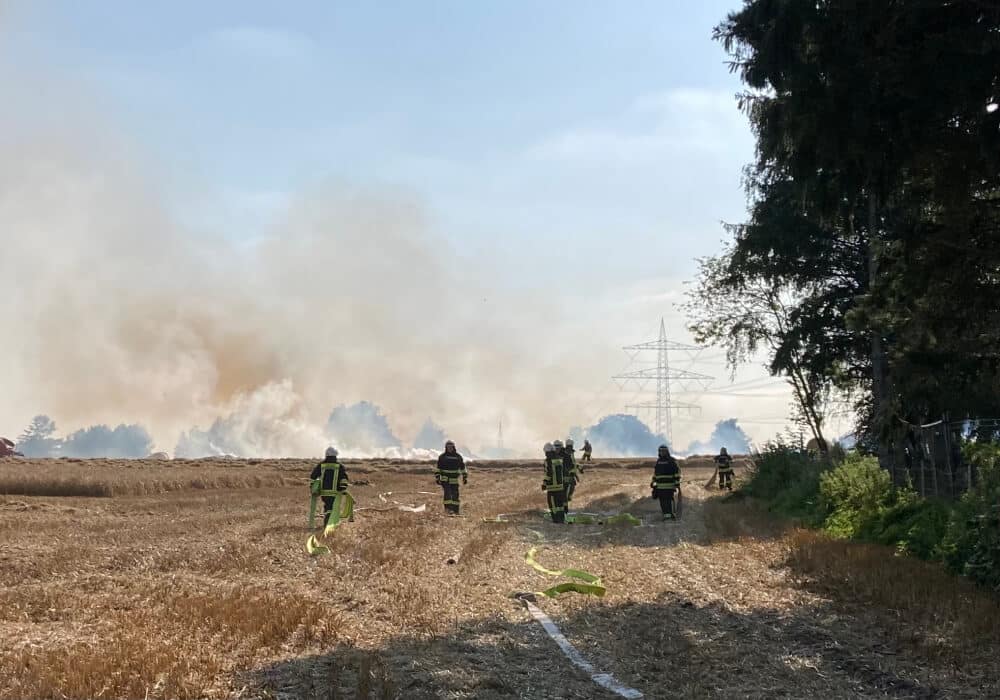 Die Feuerwehr im Einsatz. Im Hintergrund sieht man den Rauch aufsteigen.