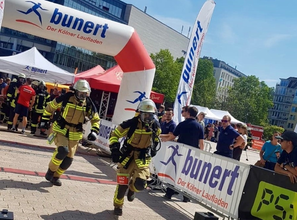 Mit ihrer gesamten Ausrüstung laufen die Einsatzkräfte für den Verein km4kids beim Kölnturm Treppenlauf.