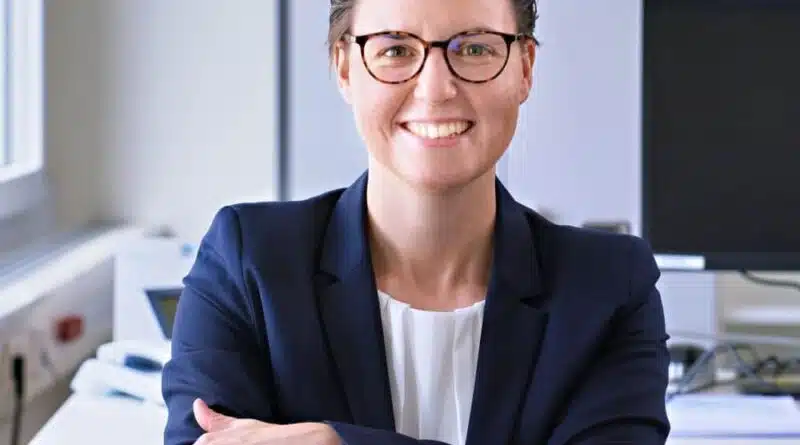 Lena Wieland in einem Büro mit Computern im Hintergrund.