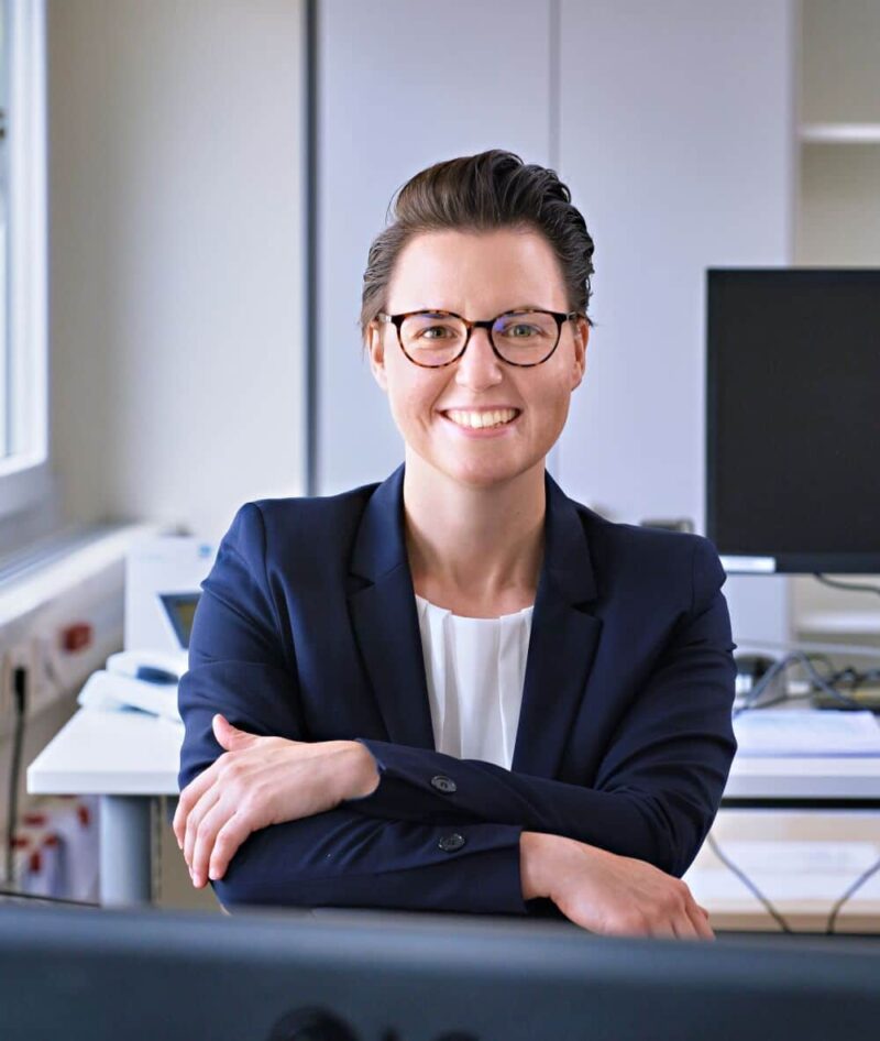 Lena Wieland in einem Büro mit Computern im Hintergrund.