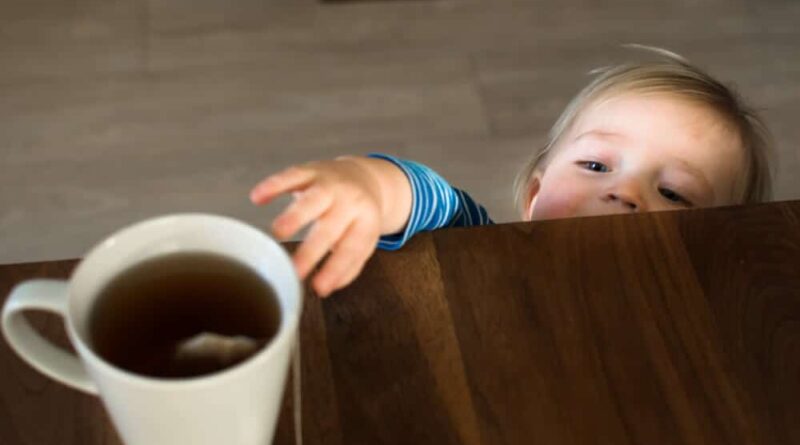 Kind greift nach heisser Teetasse