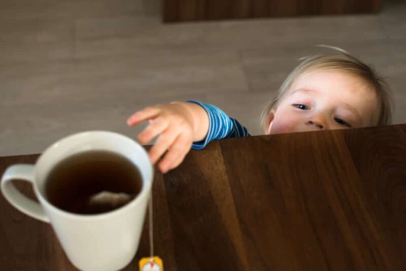 Kind greift nach heisser Teetasse