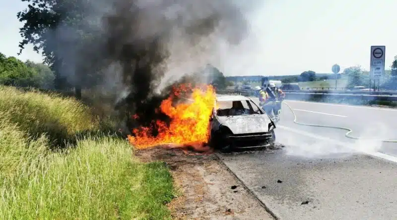 Lagebild: Brennnendes Auto und Böschungsbrand am Fahrbahnrand der A1.