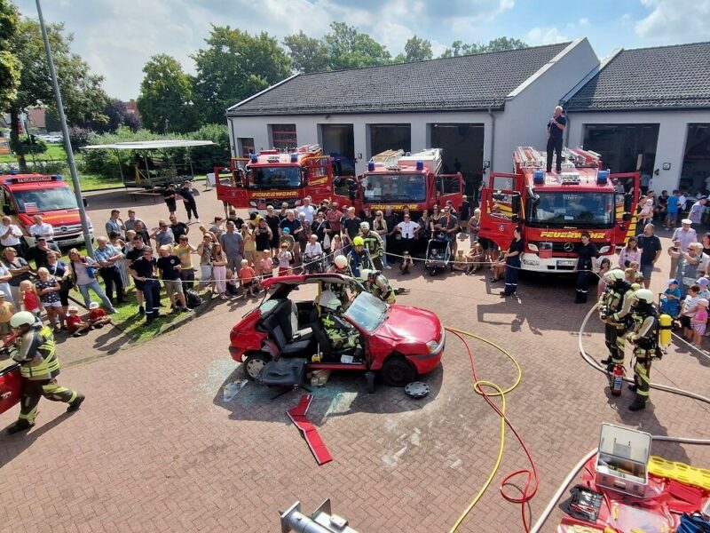 Inmitten der Feuerwehrfahrzeuge demonstrieren die Feuerwehrleute, wie sie Menschen nach Verkehrsunfällen aus einem Auto retten.