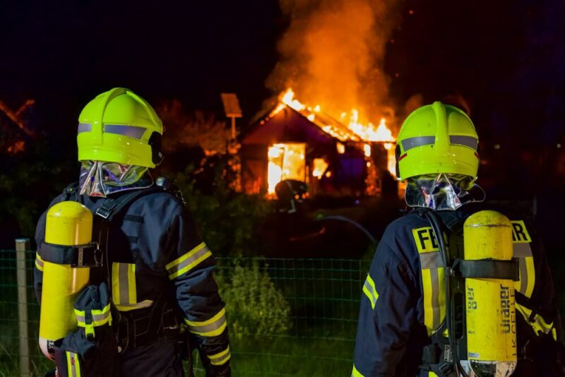 Zwei Einsatzkräfte der Feuerwehr begutachten den Brand im Schrebergarten.