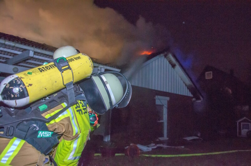 Feuerwehrkraft löscht die Flammen beim Dachstuhlbrand.