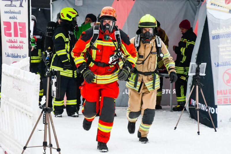 Ein Team aus zwei Feuerwehrmännern sprintet los. Alle Teilnehmer tragen ihre komplette persönliche Schutzausrüstung plus Druckluftatmer.