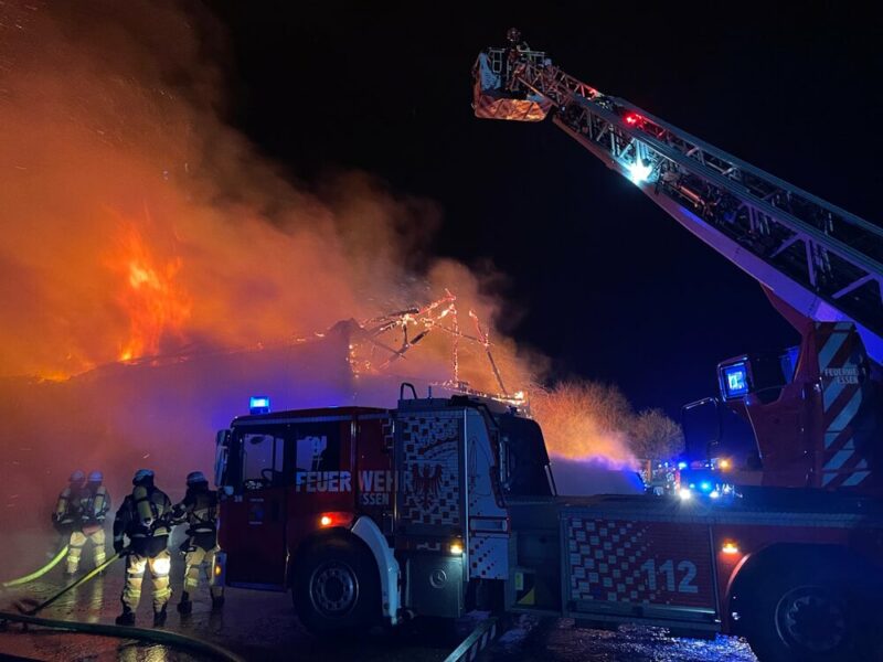 Großbrand in einer Reiterhalle. Davor steht eine Drehleiter.