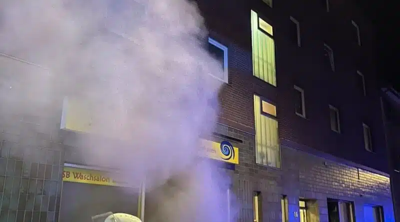Eine Einsatzkraft mit Atemschutz vor dem verrauchten Waschsalon an der Vorderseite des Gebäudes. Foto: Feuerwehr Bremerhaven